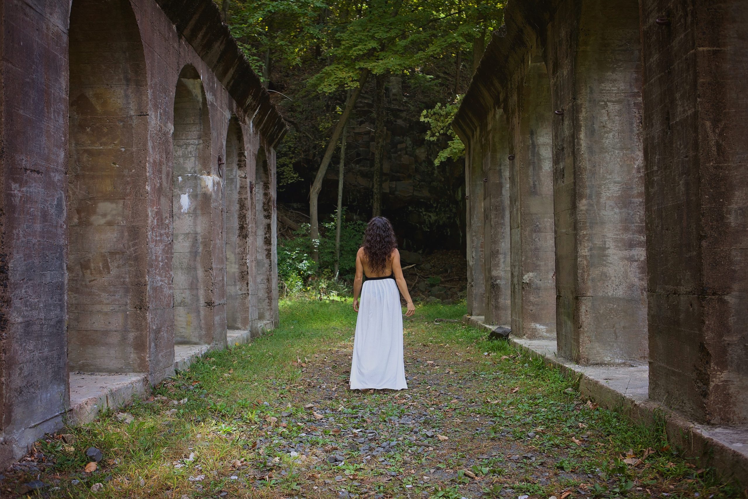 woman with a white skirt looking at large stone pillars