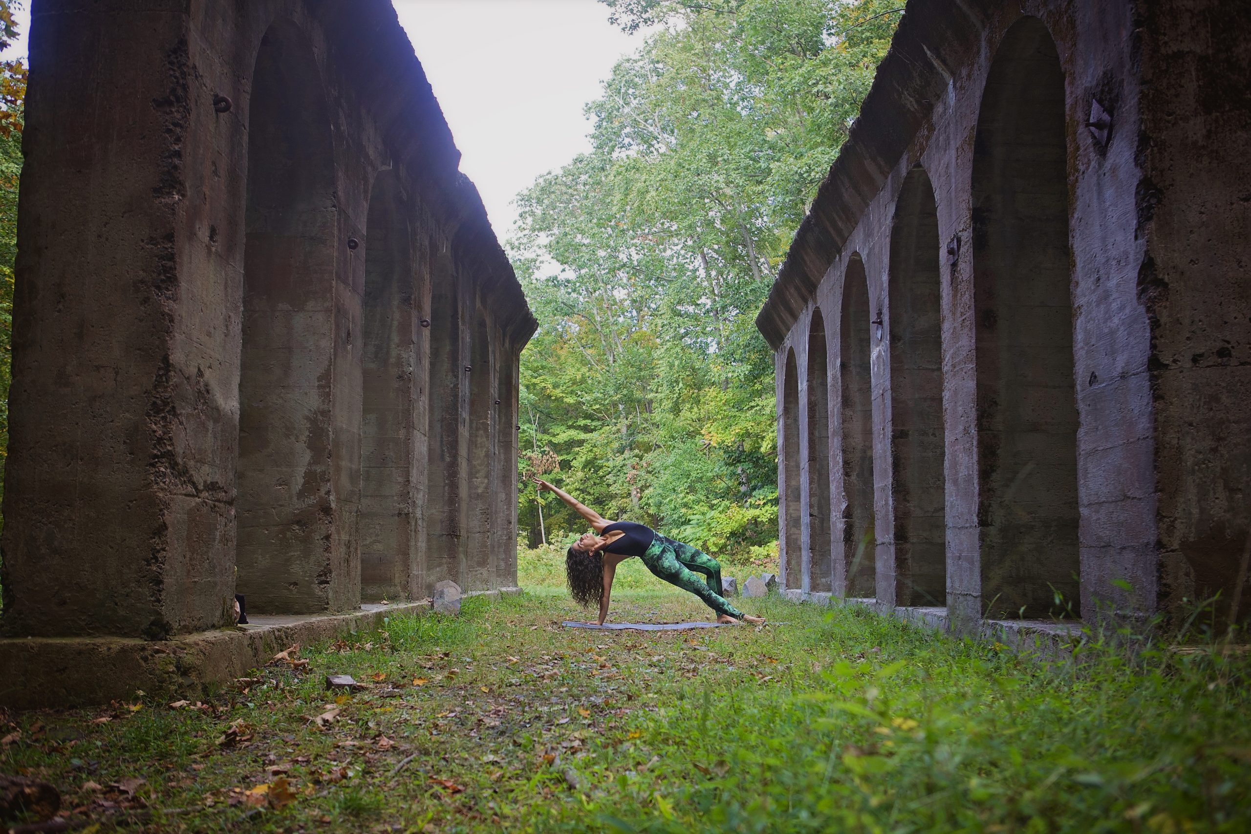 woman doing a stretch on the ground between stone structures