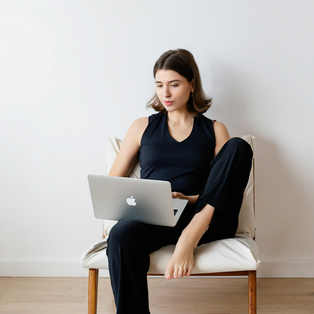 a woman wearing black clothes working on a laptop