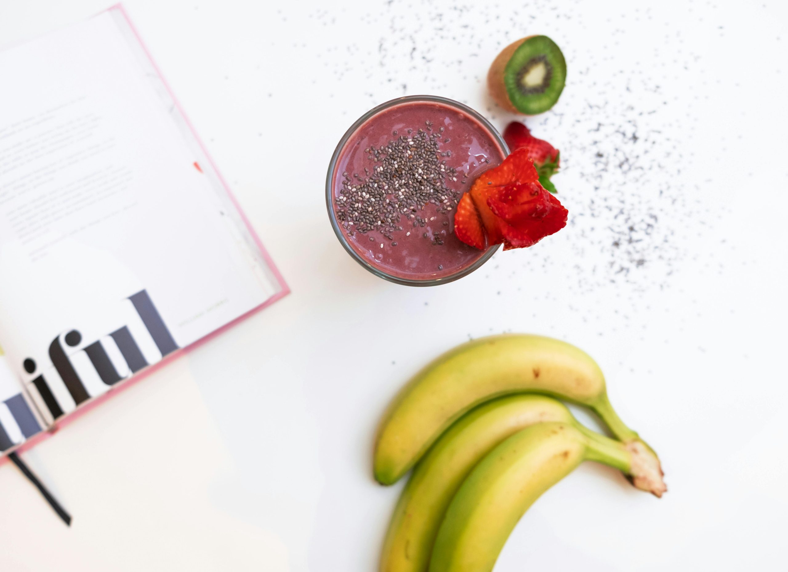 a smoothie and other fruits resting on a white table